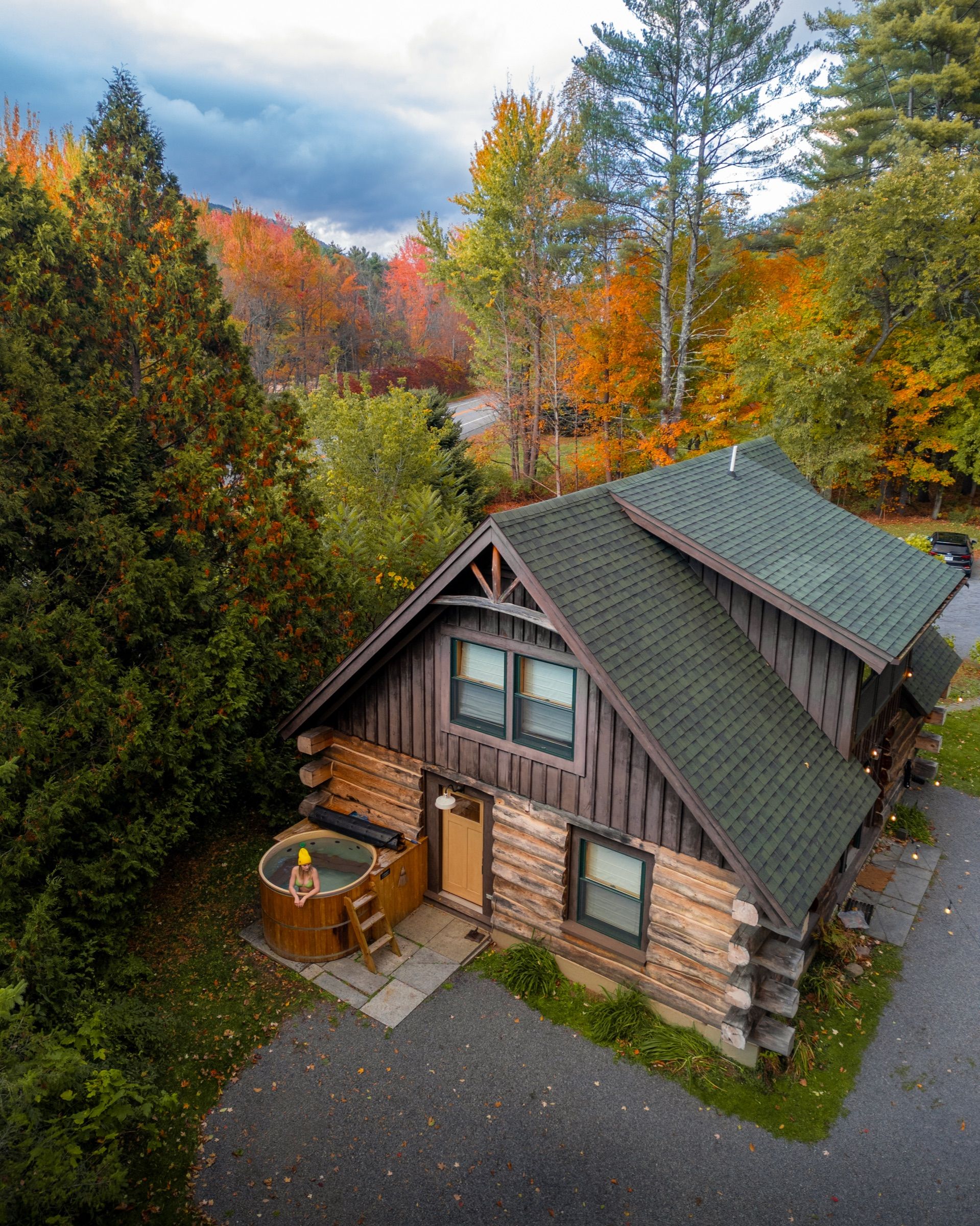 Aerial view of a log cabin with a green roof and a wooden hot tub