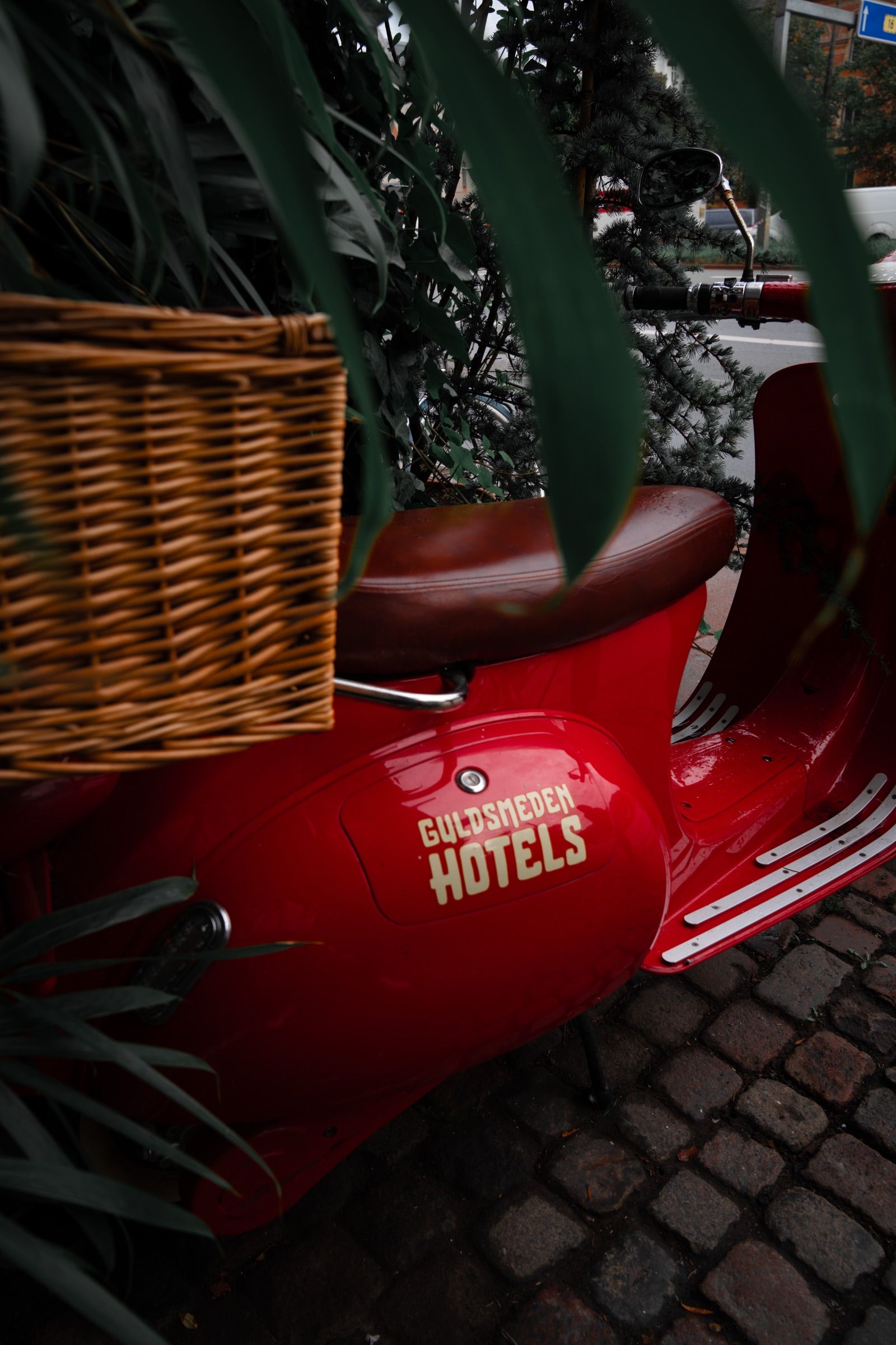 Red Vespa-style scooter with a wicker basket and a Guldsmeden Hotels logo