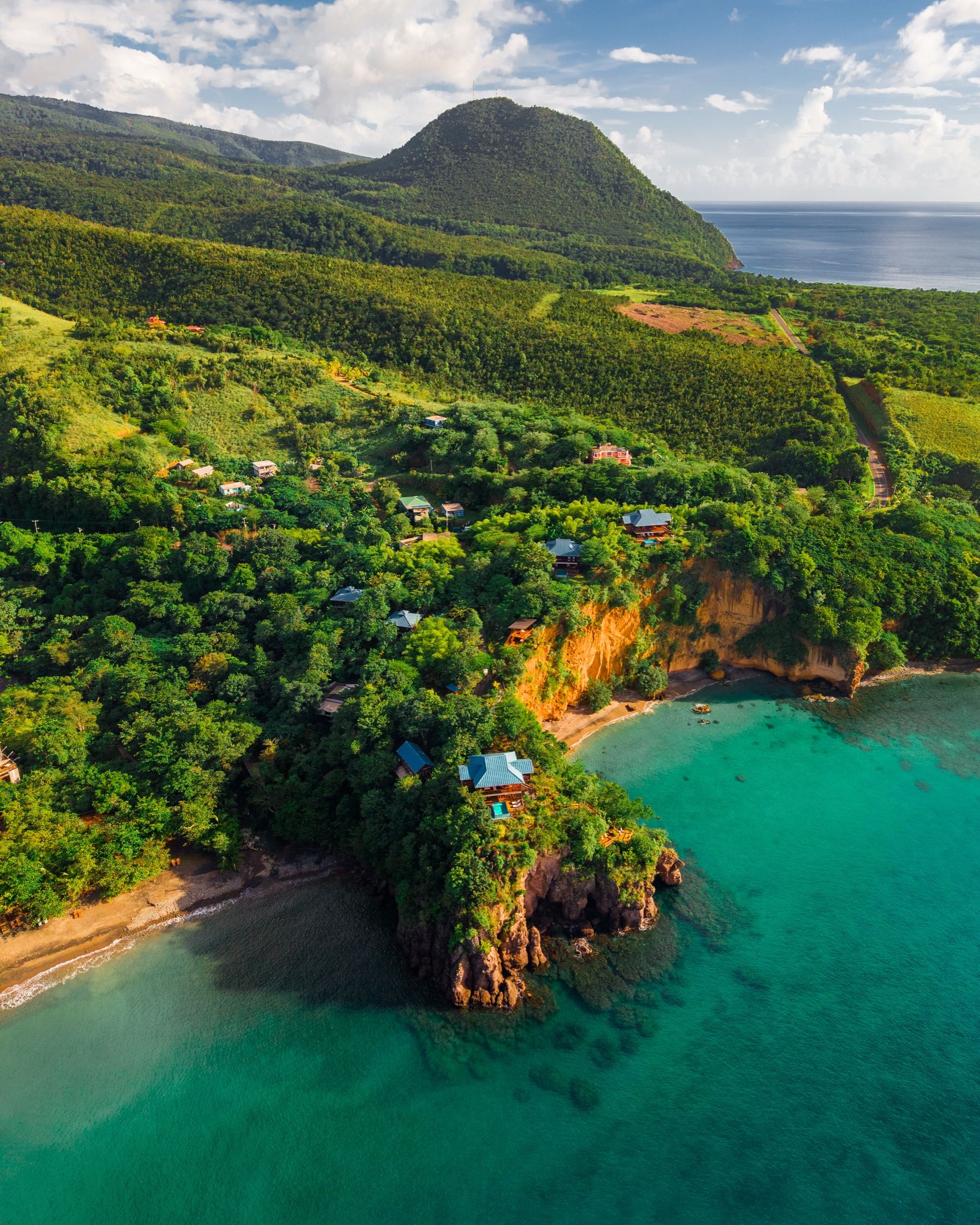 Aerial view of villas on a jungle-covered headland above a turquoise bay