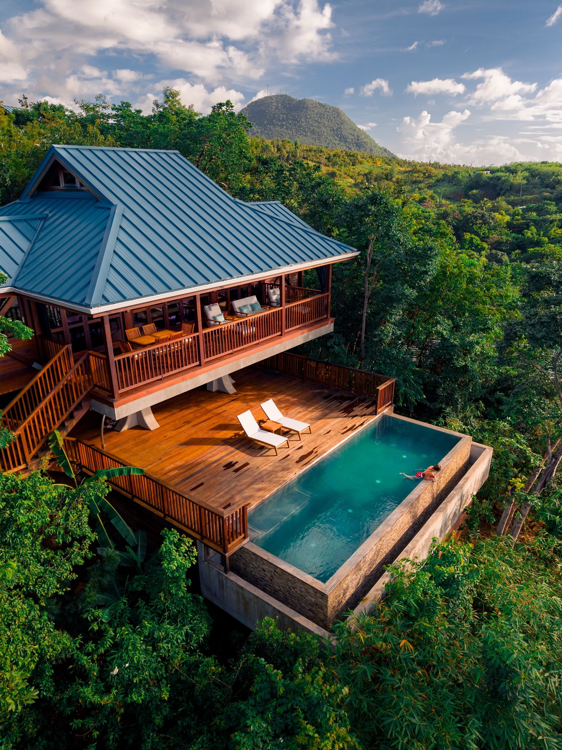 Aerial view of a tin-roofed villa with a deck and plunge pool in the rainforest